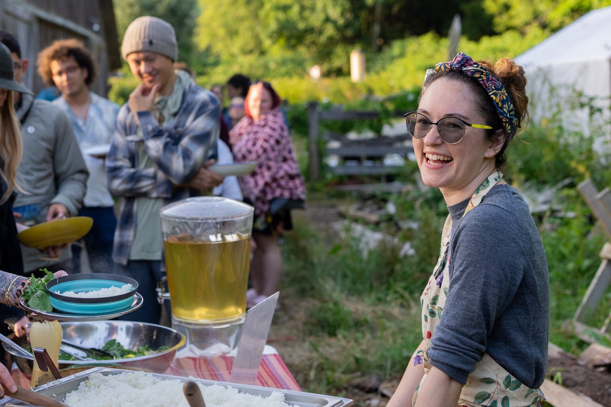 Chef smiling warmly while serving at outdoor catering event