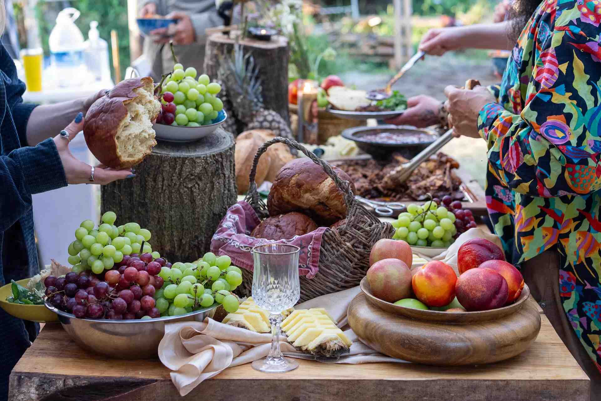 Outdoor feast with fresh bread, grapes, and seasonal produce